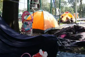 Some individuals in the caravan had tents. Others made do with tarps and blankets hung up with rope and telephone wires. The Ciudad Deportiva is scattered with strollers, teddy bears, and other belongings of children and families. Photo by Lily Folkerts.